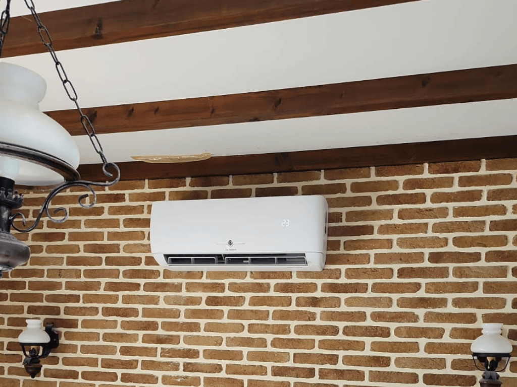 Unité intérieure murale de pompe à chaleur air/air installée sur un mur en briques dans une habitation.